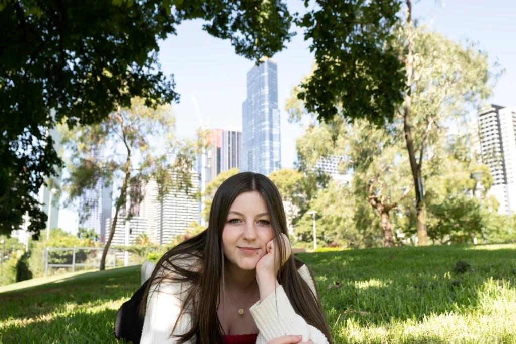 A picture of Sienna laying on grass with Melbourne city in the background