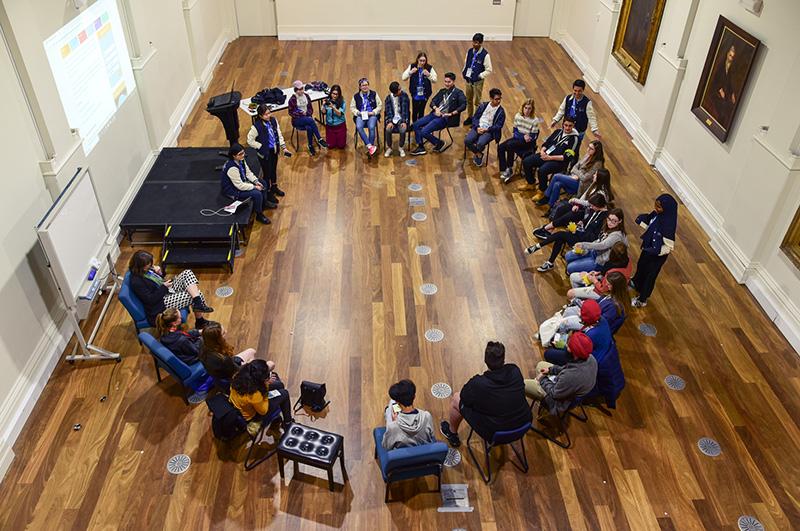 A birds-eye view of a large group of students sitting on chairs and talking